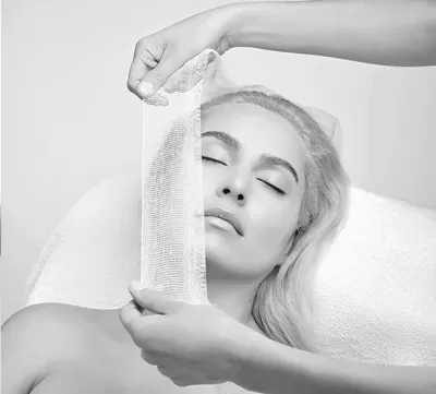 Mulher a receber máscara facial translúcida num ambiente de spa