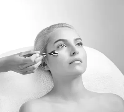 Mulher reclinada a receber massagem facial com rolo metálico