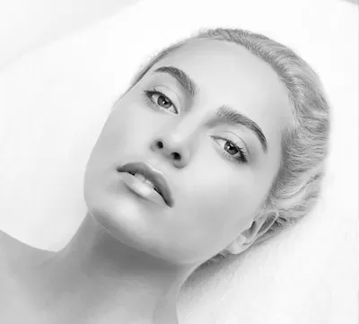 Rosto de mulher jovem com cabelo claro e pele lisa em fundo branco