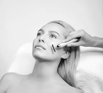 Mulher a receber tratamento facial com dispositivo eletrónico branco