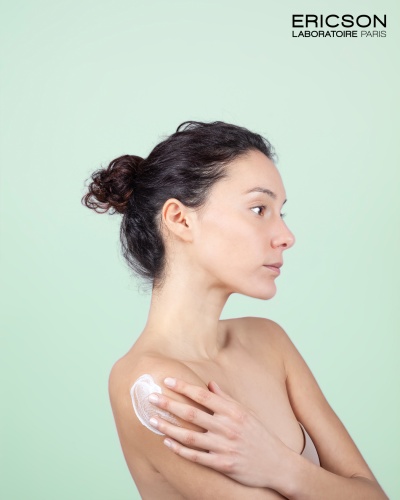Mulher a aplicar creme no ombro com fundo verde e texto ERICSON LABORATOIRE PARIS