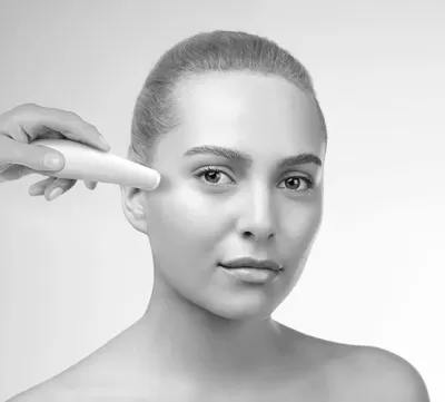 Mulher com dispositivo branco ao lado do rosto num fundo branco desfocado.