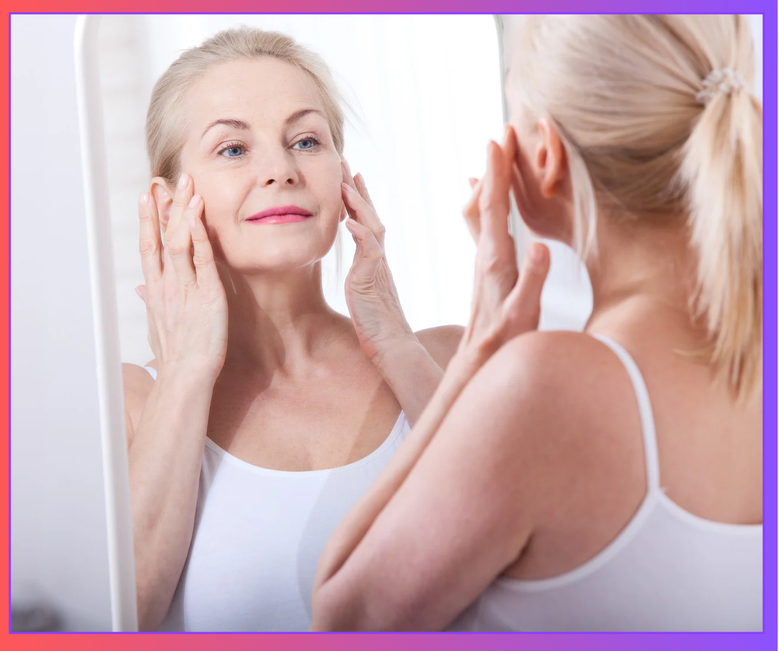 Mulher de meia-idade a tocar o rosto em frente a um espelho