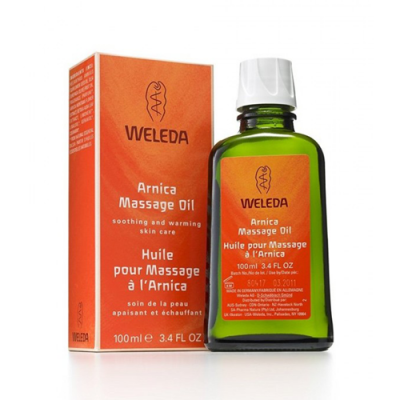 Frasco verde de Arnica Massage Oil da Weleda com caixa laranja ao lado
