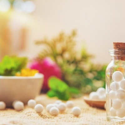 Frasco de vidro com bolas brancas e decoração floral ao fundo