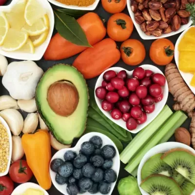 Frutas e vegetais crus variados em tigelas e espalhados sobre superfície branca