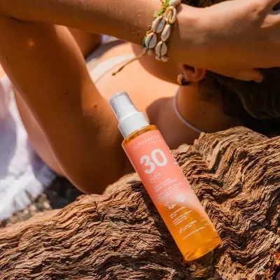Frasco de spray de proteção solar ALPHANOVA SPF 30 em madeira com braço ao fundo