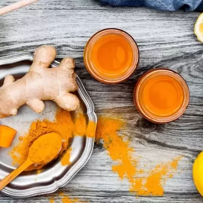 Ingredientes naturais: gengibre, cúrcuma, mel e limão dispostos em mesa de madeira.