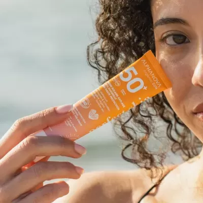 Mulher segurando tubo laranja de protetor solar Alphanova Organic Sun SPF 50+