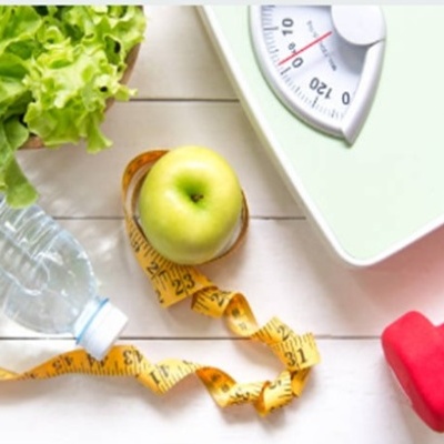 Fruta, fita métrica, alface, água, balança e haltere sobre mesa branca