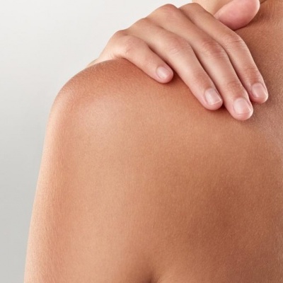 Ombro e costas de pessoa com mão repousando no ombro num fundo branco