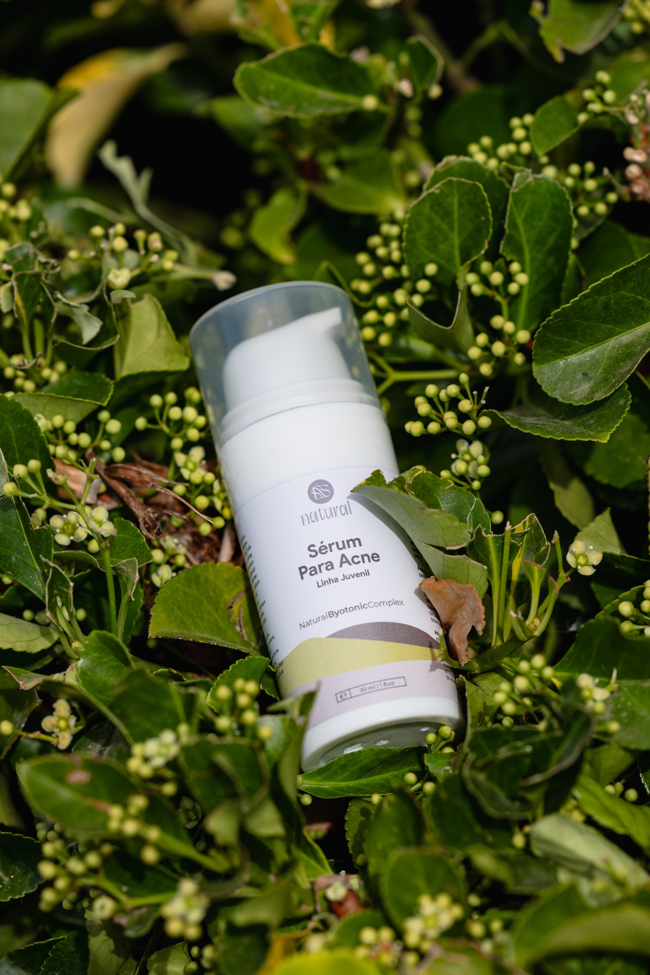 Sérum para Acne Frasco branco de sérum para acne sobre folhas verdes