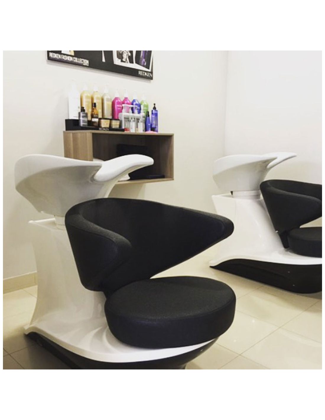 Cadeira de cabeleireiro preta e branca com produtos numa prateleira numa sala branca