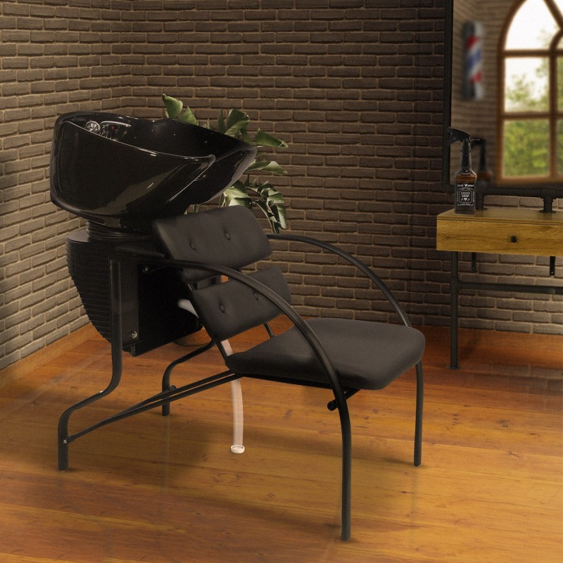 Cadeira preta com cuba de lavagem num salão com parede de tijolos e chão em madeira