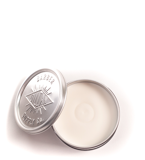 Pote metálico prateado aberto com creme branco e tampa com texto em relevo