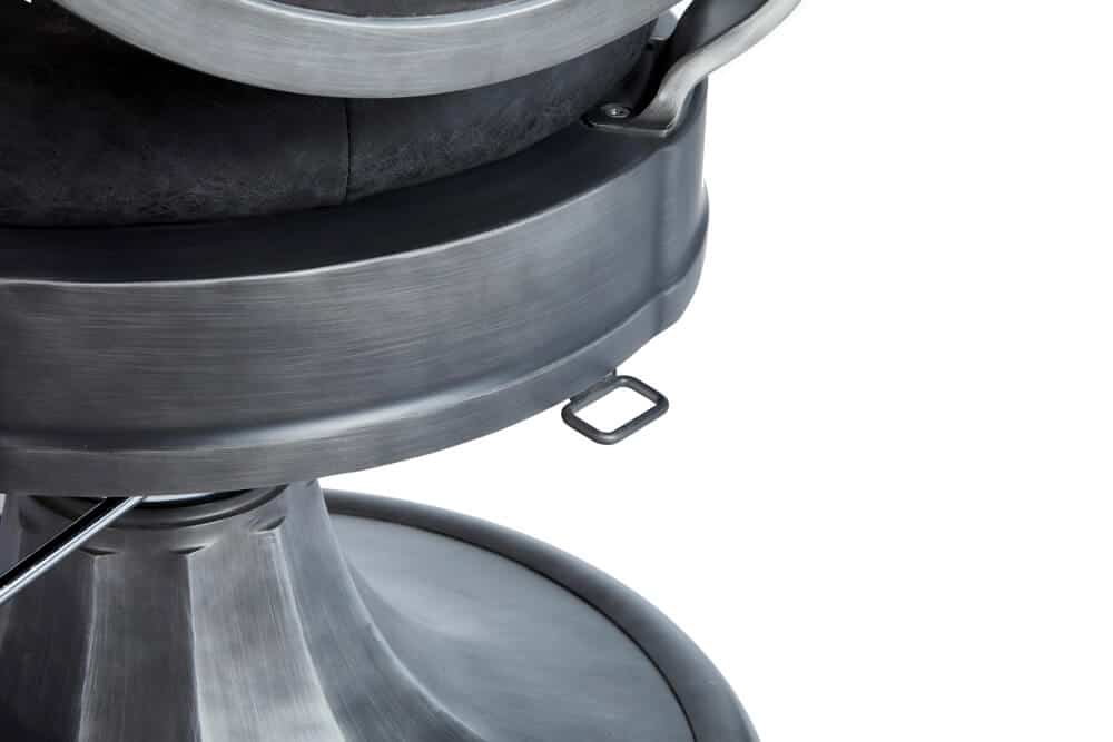 Detalhe de cadeira de barbearia em metal prateado e couro preto
