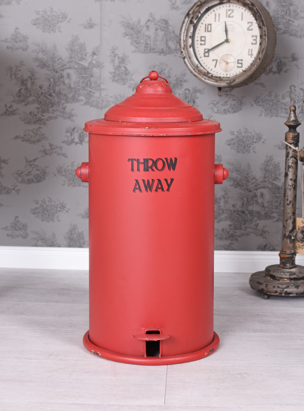 Contentor de lixo vermelho metálico com tampa e texto THROW AWAY em parede cinzenta