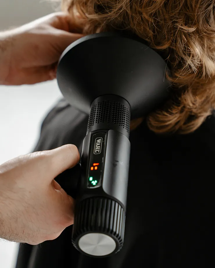 Secador de cabelo Wahl preto com visor digital a ser usado numa pessoa com cabelo castanho claro