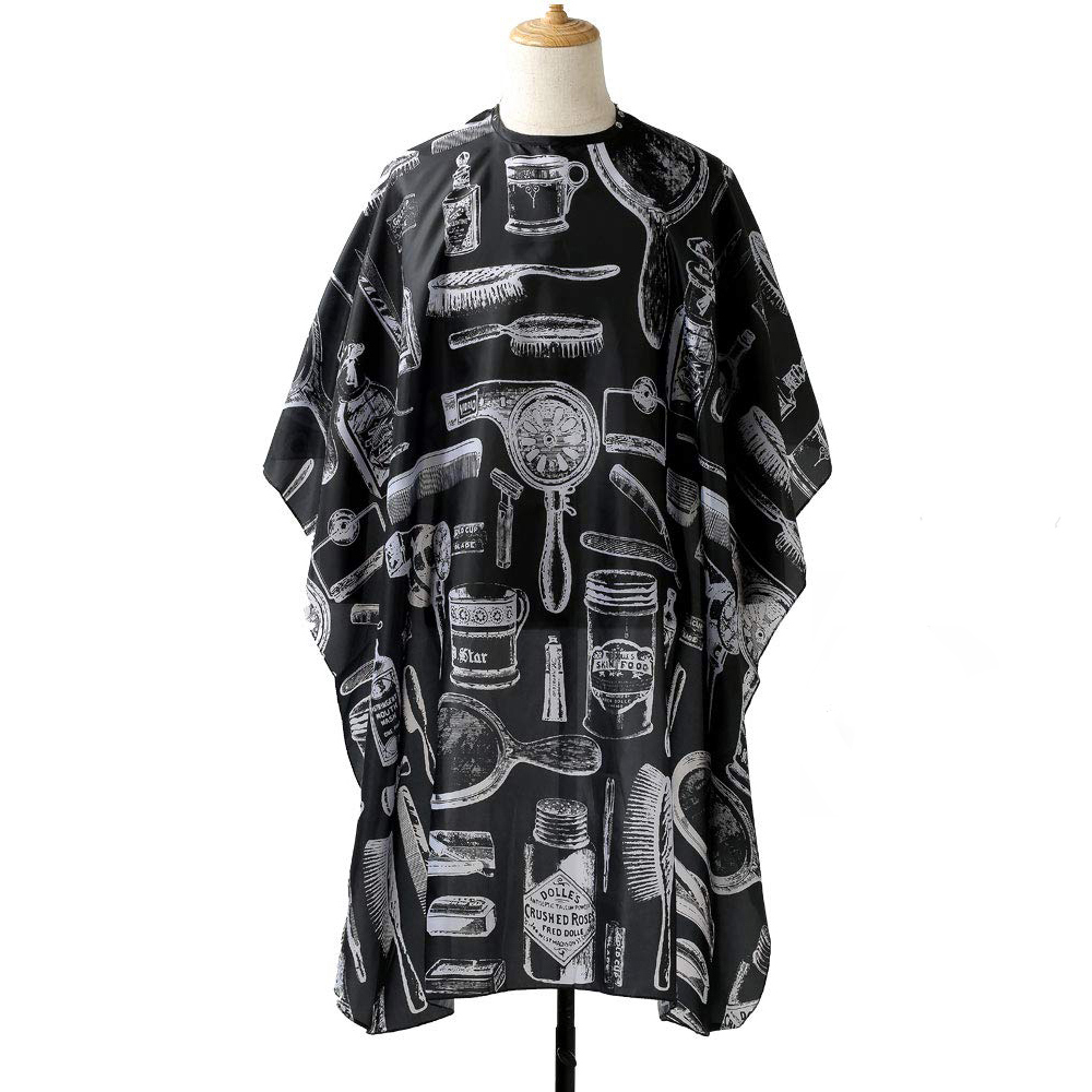 Capa preta de barbeiro com estampas brancas de objetos de barbearia sobre manequim.