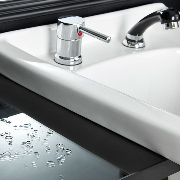 Pia branca com torneira cromada e bancada preta brilhante com gotas de água
