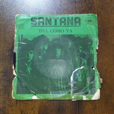 Capa de vinil verde com texto SANTANA e imagem de grupo