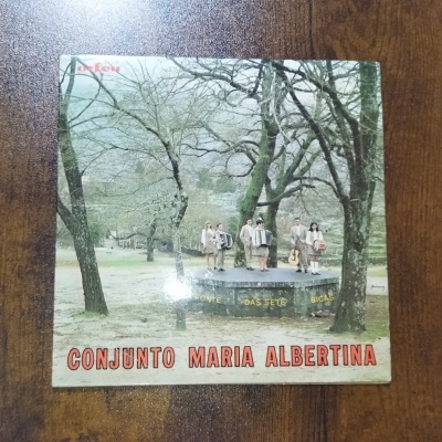 Capa de disco com cinco músicos em plataforma e árvores secas ao redor