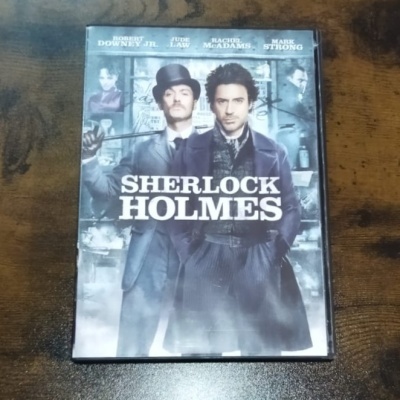 Capa do filme Sherlock Holmes com dois personagens em trajes antigos, nomes dos atores e título em destaque.