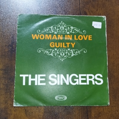 Capa de disco vinil verde com texto Woman in Love Guilty e The Singers em madeira.