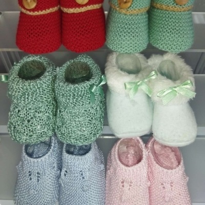 Sapatinhos de bebé em várias cores e texturas organizados numa superfície