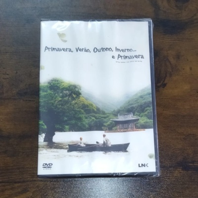 Capa de DVD com imagem de dois homens numa canoa num lago e texto 'Primavera, Verão, Outono, Inverno... e Primavera'