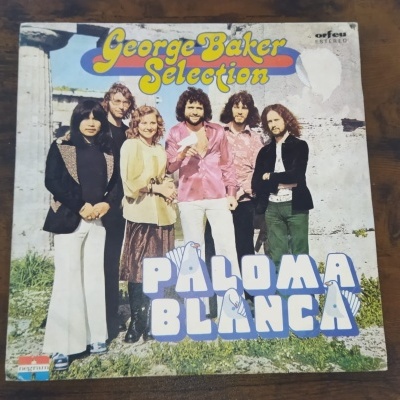 Capa de disco vinil George Baker Selection Paloma Blanca com seis pessoas em fundo ao ar livre