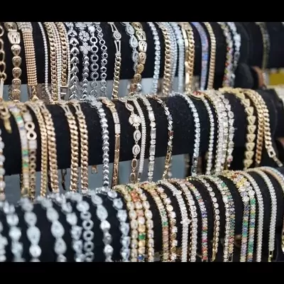 Pulseiras de bijuteria douradas e prateadas com pedras coloridas em suportes pretos.