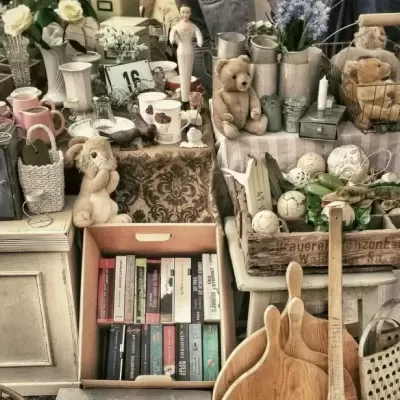 Mesa vintage com utensílios diversos, incluindo ursos de pelúcia, canecas, livros e decoração