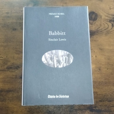 Capa cinzenta de livro 'Babbitt' de Sinclair Lewis com texto branco e imagem oval de cidade