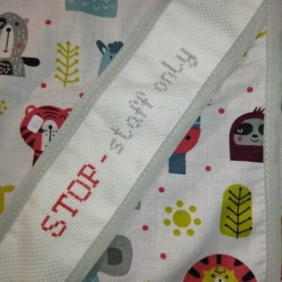 tecido branco com animais coloridos e faixa bordada com texto stop