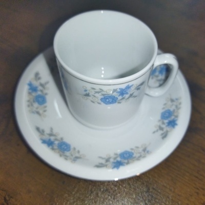 Chávena e pires em porcelana branca com flores azuis e folhas verdes