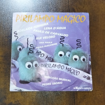 Capa do álbum Pirilampo Mágico com personagens verdes peludos e texto branco e amarelo