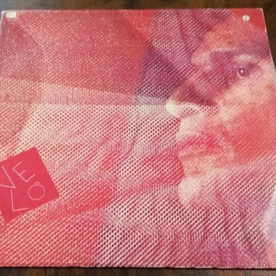 Capa de álbum de vinil vermelha texturizada com imagem de rosto e texto VELO