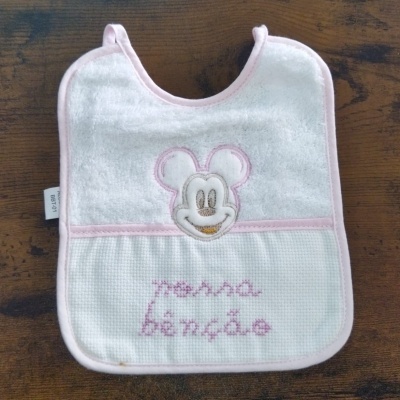 Babete de bebé branco com bordado rosa e figura sorridente