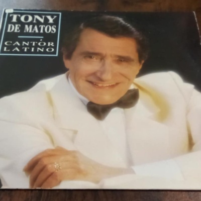Capa de álbum de vinil Tony de Matos com fotografia de homem de fato branco e laço preto