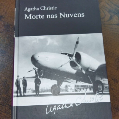 Livro Morte nas Nuvens de Agatha Christie com capa em preto e branco mostrando um avião e quatro pessoas
