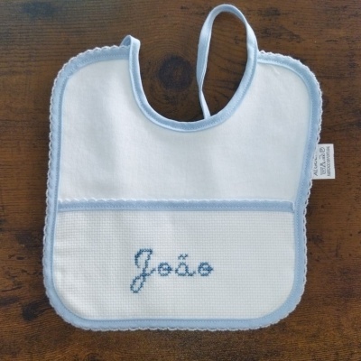 Babete de bebé branco com borda azul e nome João bordado