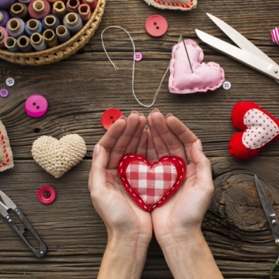 Mesa de madeira com corações de tecido, botões, tesouras e linha para costura