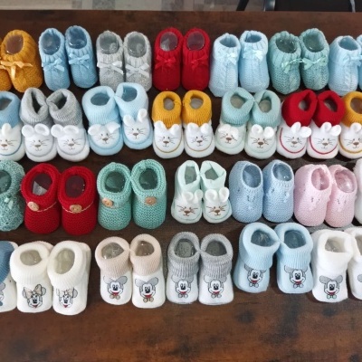 Botins de bebé em várias cores e desenhos sobre mesa de madeira
