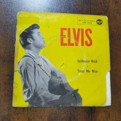 Capa amarela de disco vinil com imagem a preto e branco de jovem com guitarra e texto ELVIS