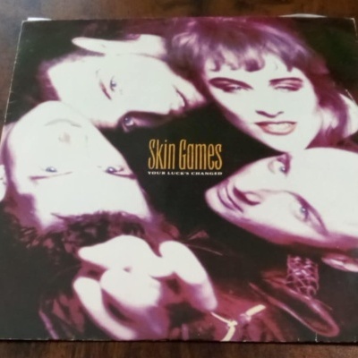 Capa de álbum em vinil com quatro rostos e texto Skin Games