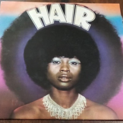 Capa de álbum com mulher de cabelo afro e colar, palavra HAIR no topo