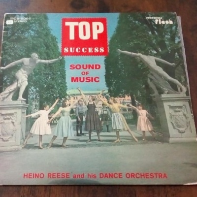 Capa de disco vinil com dança e esculturas de pedra ao ar livre