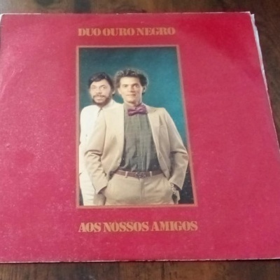 Capa de disco vinil vermelho do Duo Ouro Negro com foto de dois homens no centro.