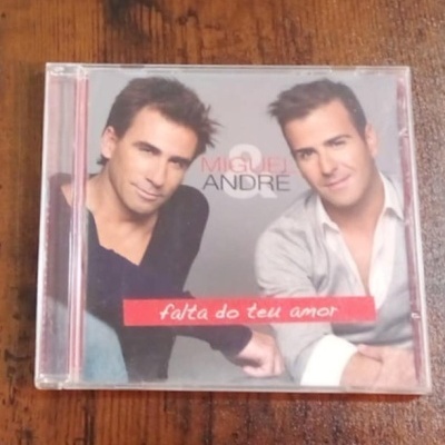 Capa de CD com duas pessoas e texto 'MIGUEL & ANDRÉ' e 'falta do teu amor'.